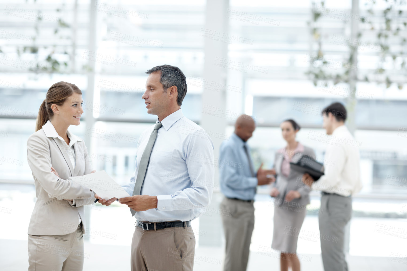 Buy stock photo Businesspeople having a discussion with their colleagues in the background