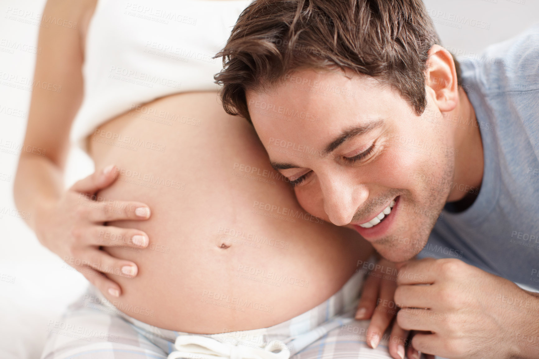 Buy stock photo Couple, happy and pregnant with stomach, listening and bonding in home for future motherhood hope. People, support and healthy pregnancy development for prenatal care, maternity and growth with relax