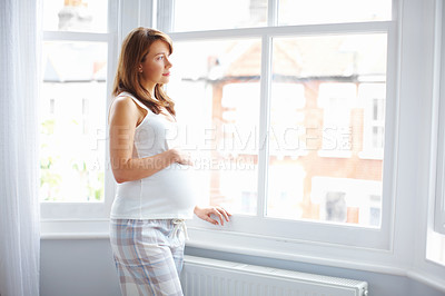 Buy stock photo A beautiful pregnant woman looking out of the window thoughtfully