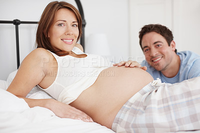 Buy stock photo An expectant couple lying in bed together