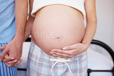 Buy stock photo An expectant mother holding hands with her husband and touching her baby bump