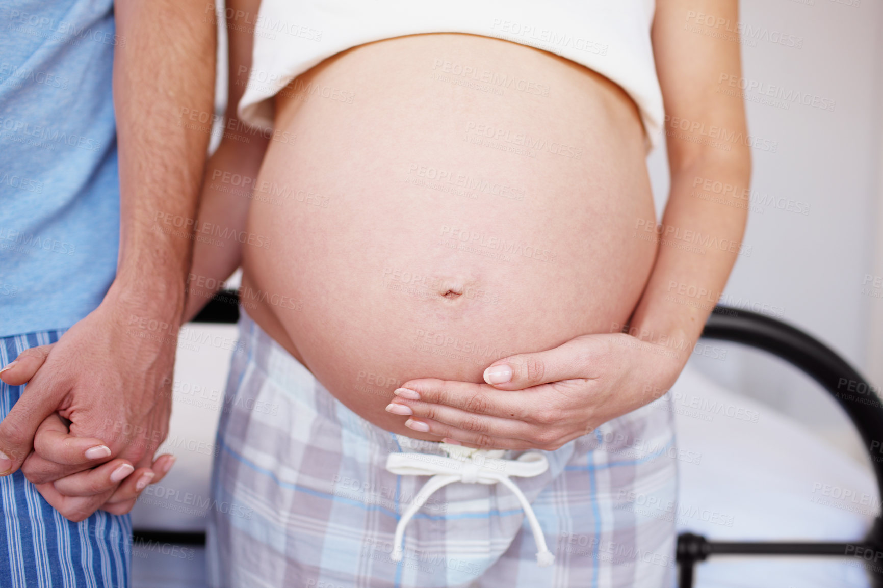 Buy stock photo An expectant mother holding hands with her husband and touching her baby bump