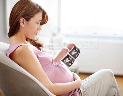 Buy stock photo A beautiful pregnant woman looking at ultrasound scans of her baby - Copyspace