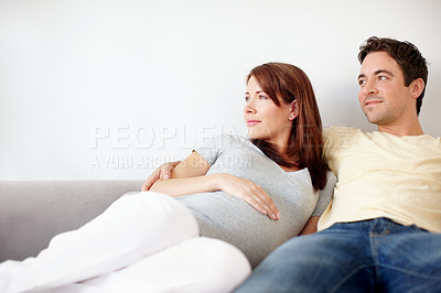 Buy stock photo A blissful, expecting couple looking towards copyspace thoughtfully