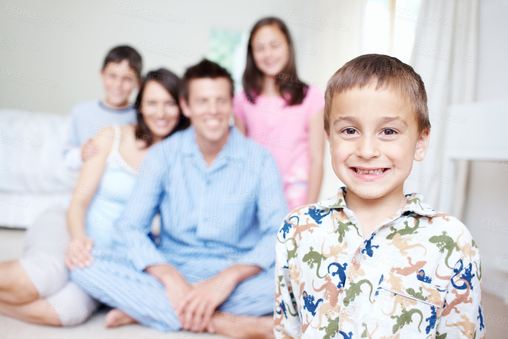 Buy stock photo Bedroom, pajamas and portrait of happy boy with family blur in home for support, love or wellness. Weekend, mother or dad with toddler, children or growth for bonding together with parents in morning