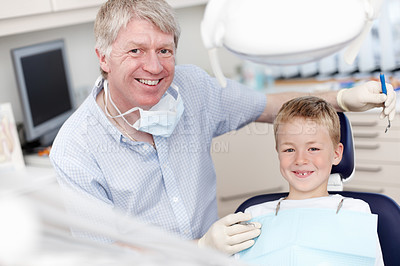 Buy stock photo Portrait of mature dentist smiling with child at clinic