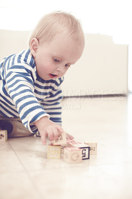 Buy stock photo A cute baby boy at home on the floor, playing with some wooden blocks