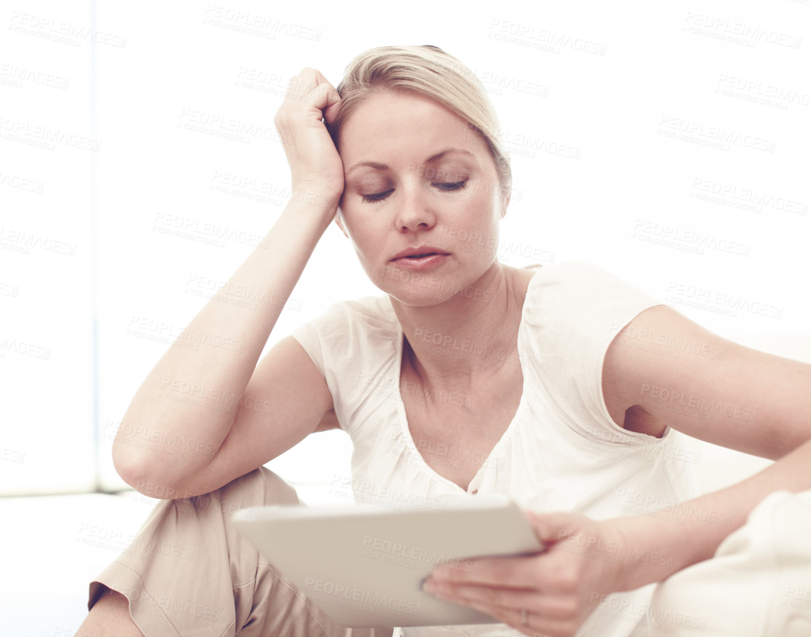 Buy stock photo An attractive blonde woman using a tablet while sitting at home