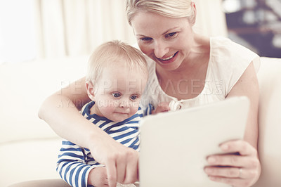 Buy stock photo An attractive young mother showing her curious baby a touchscreen tablet
