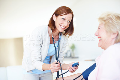 Buy stock photo Mature smiling nurse checks an elderly female patient's blood pressure