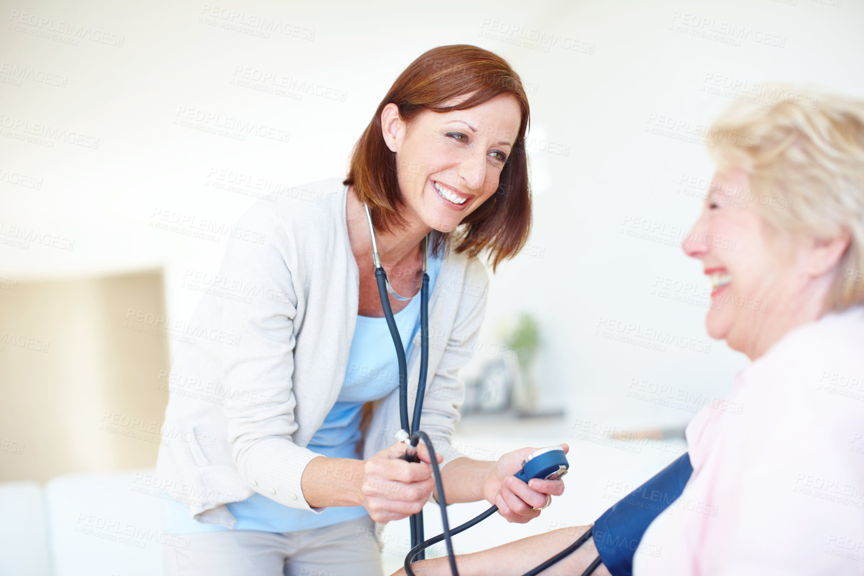 Buy stock photo Mature smiling nurse checks an elderly female patient's blood pressure