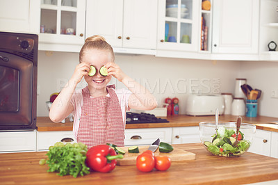 Buy stock photo Vegetables, cucumber on eyes and child in kitchen for healthy eating, wellness and vegetarian diet. Silly, vitamins and young girl in home with organic ingredients for lunch, dinner and meal prep