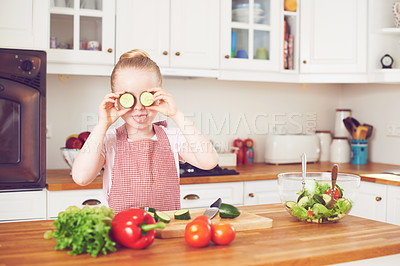 Buy stock photo Vegetables, cucumber on eyes and silly kid in kitchen for healthy eating, wellness and vegetarian diet. Food, home and goofy and young girl with organic ingredients for lunch, dinner and meal prep