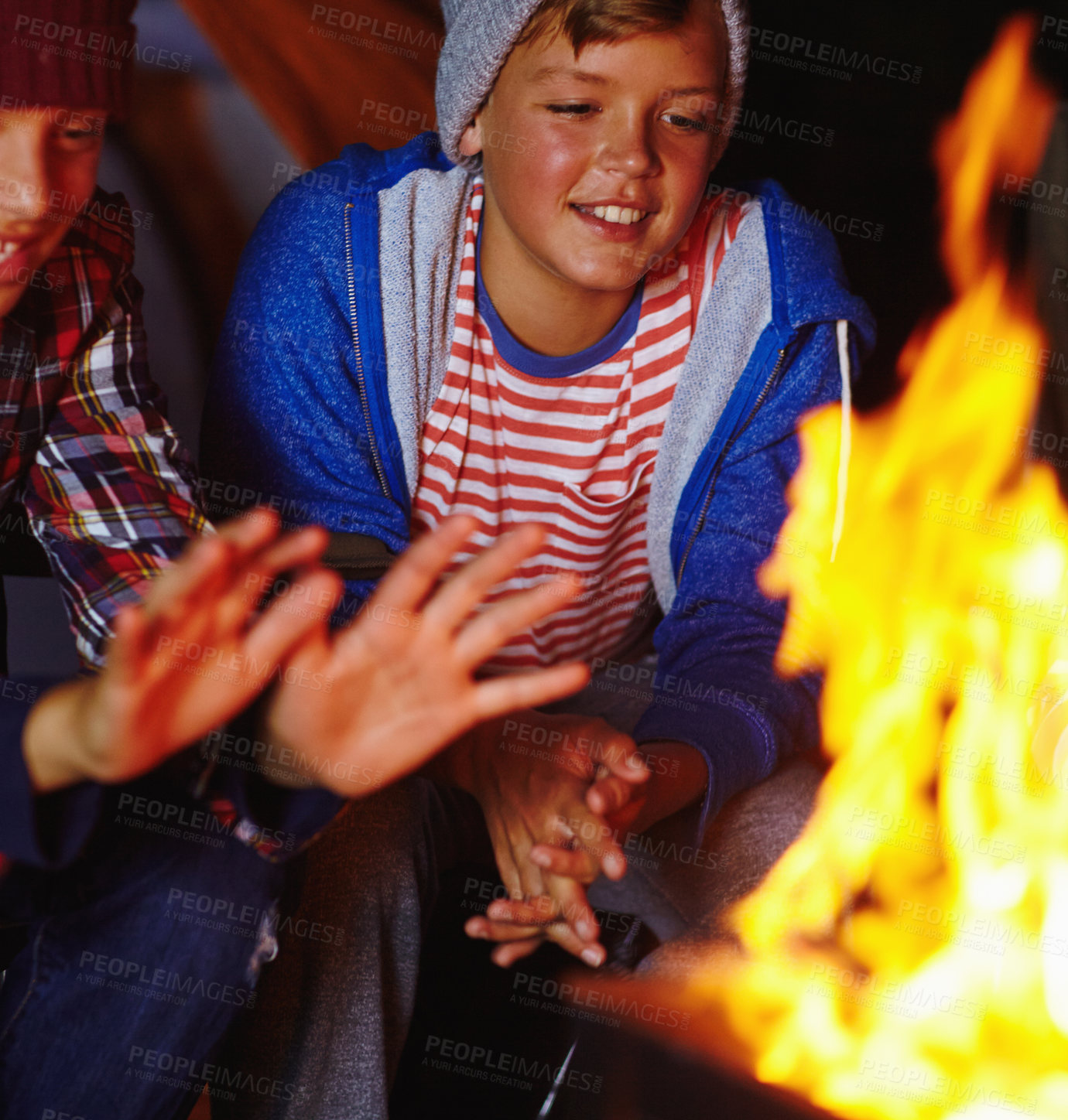 Buy stock photo Cropped shot of two young boys sitting by the campfire