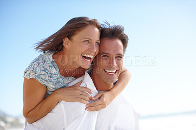 Buy stock photo Portrait of a mature man giving his happy wife a piggyback at the beach