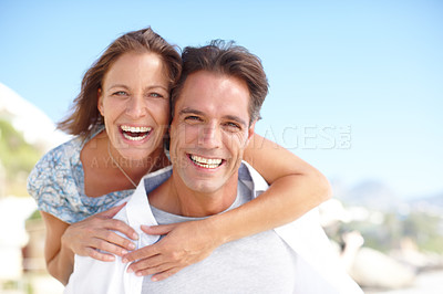 Buy stock photo Portrait of a mature man giving his happy wife a piggyback at the beach