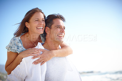 Buy stock photo A mature man giving his happy wife a piggyback at the beach