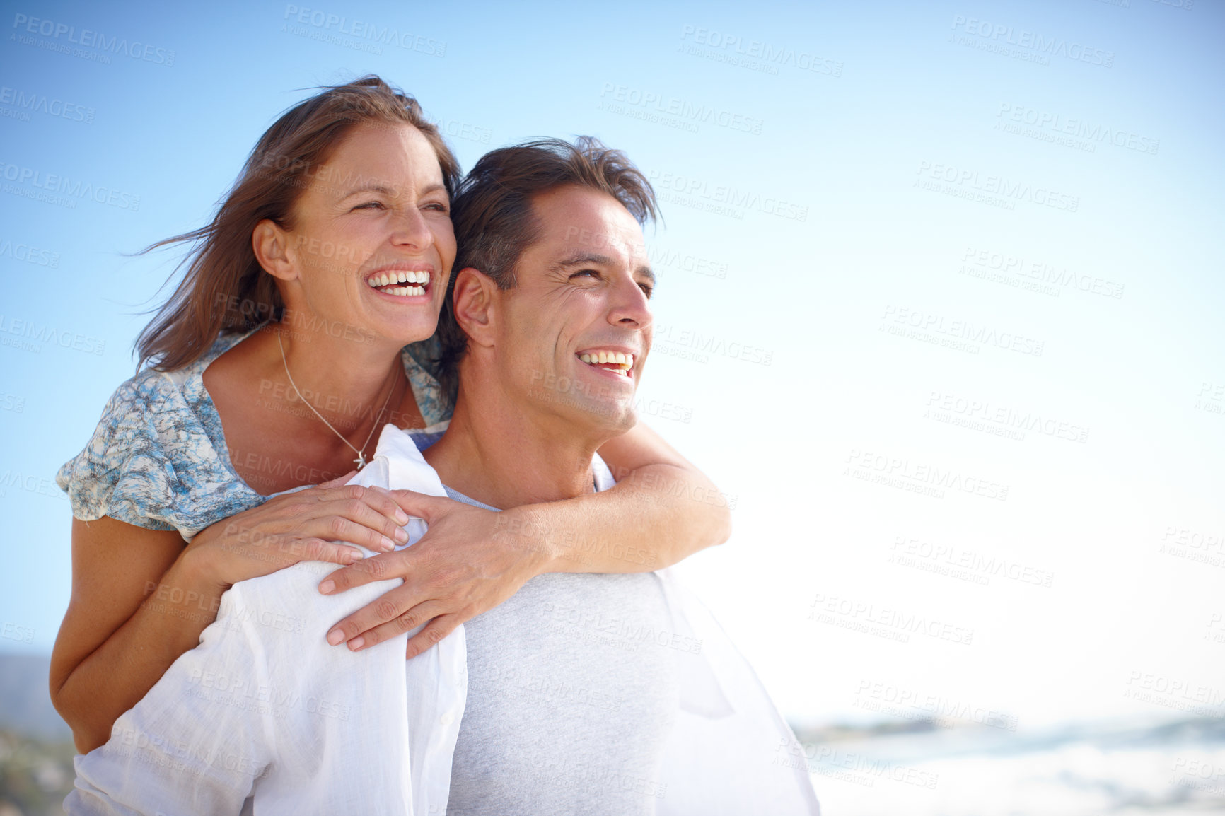 Buy stock photo Beach, piggyback and couple with smile, outdoor and holiday for romance, date and happy in relationship. Hug, man and woman on vacation, bonding and commitment in marriage, space and valentines day