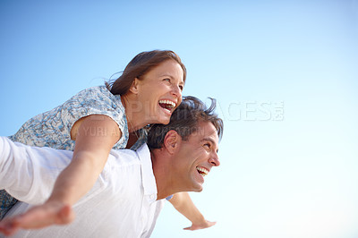 Buy stock photo A mature man with his happy wife on his back both with their arms outstretched