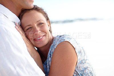 Buy stock photo A mature man embracing his happy wife from behind as they stand on the beach