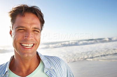 Buy stock photo Portrait of a handsome man smiling on the beach alongside copyspace