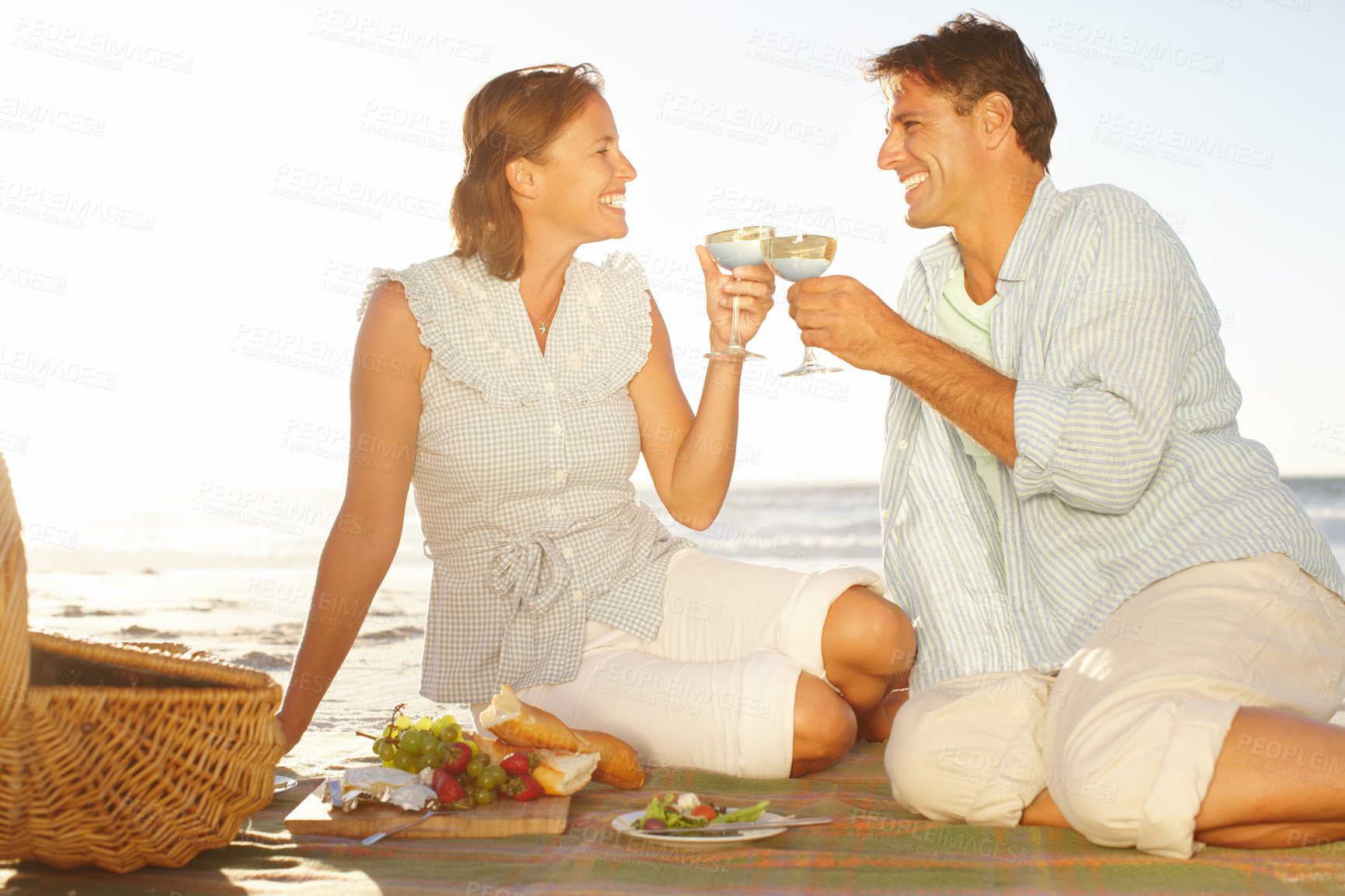 Buy stock photo A loving mature couple enjoying a romantic picnic on the beach together