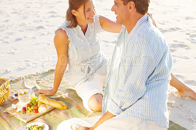 Buy stock photo A devoted couple enjoying a romantic picnic on the beach together