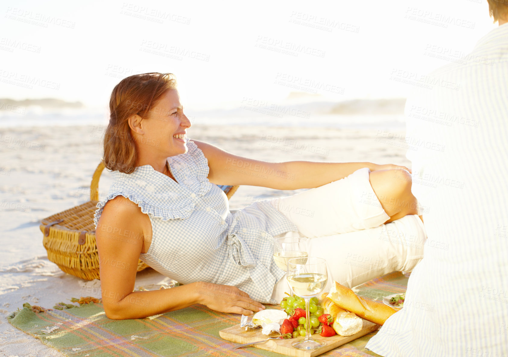 Buy stock photo Sunset, beach picnic and couple with love, wine and view for summer vacation in Miami. Man, woman and smile with basket, sea holiday and happy bonding for relationship anniversary or weekend by ocean