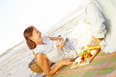 Buy stock photo A happy mature woman relaxing on a picnic blanket and enjoying the sunset with her husband