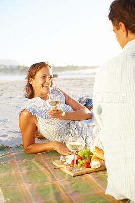 Buy stock photo A happy mature woman relaxing on a picnic blanket and enjoying the sunset with her husband