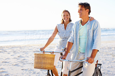 Buy stock photo A mature couple enjoying a bike ride on the beach together