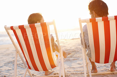 Buy stock photo A mature couple enjoying a beautiful sunset in deckchairs on the beach
