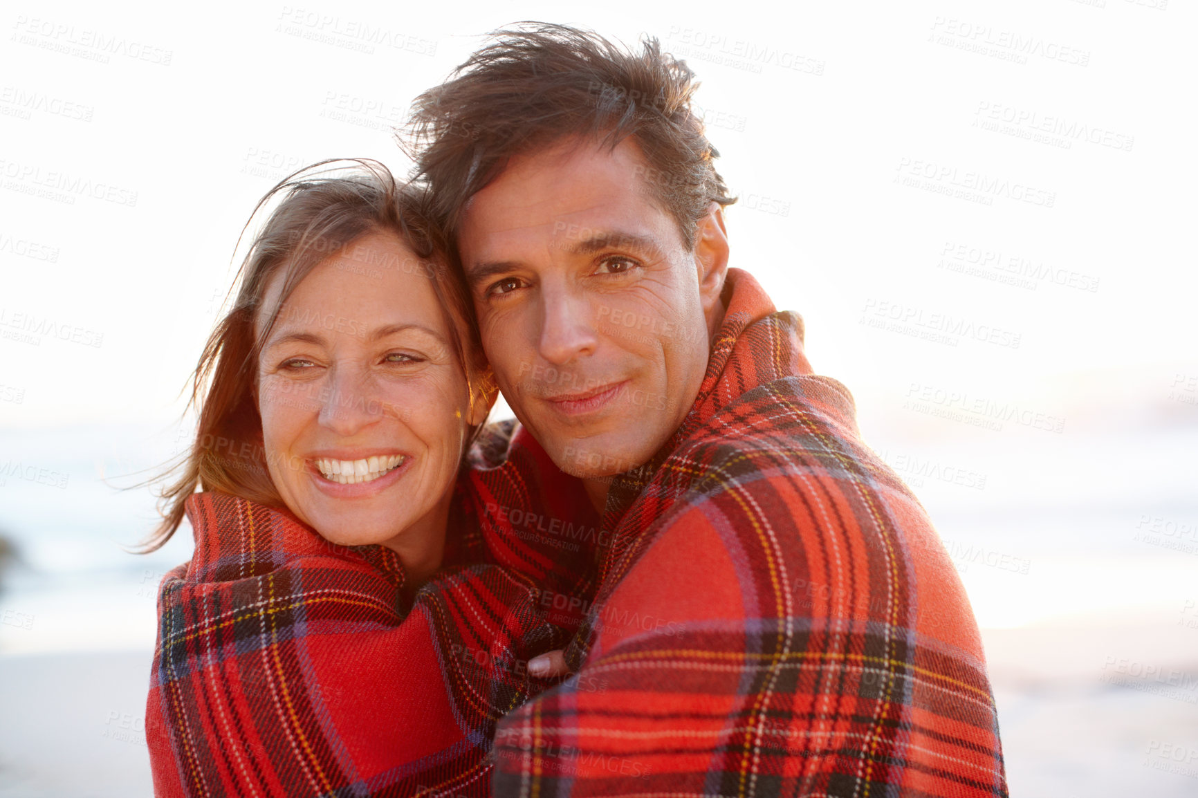 Buy stock photo Hug, blanket or couple at beach for portrait or love on vacation, anniversary or honeymoon holiday. Smile, cold or people with smile on date at sea together for travel, bonding or ocean trip in Spain