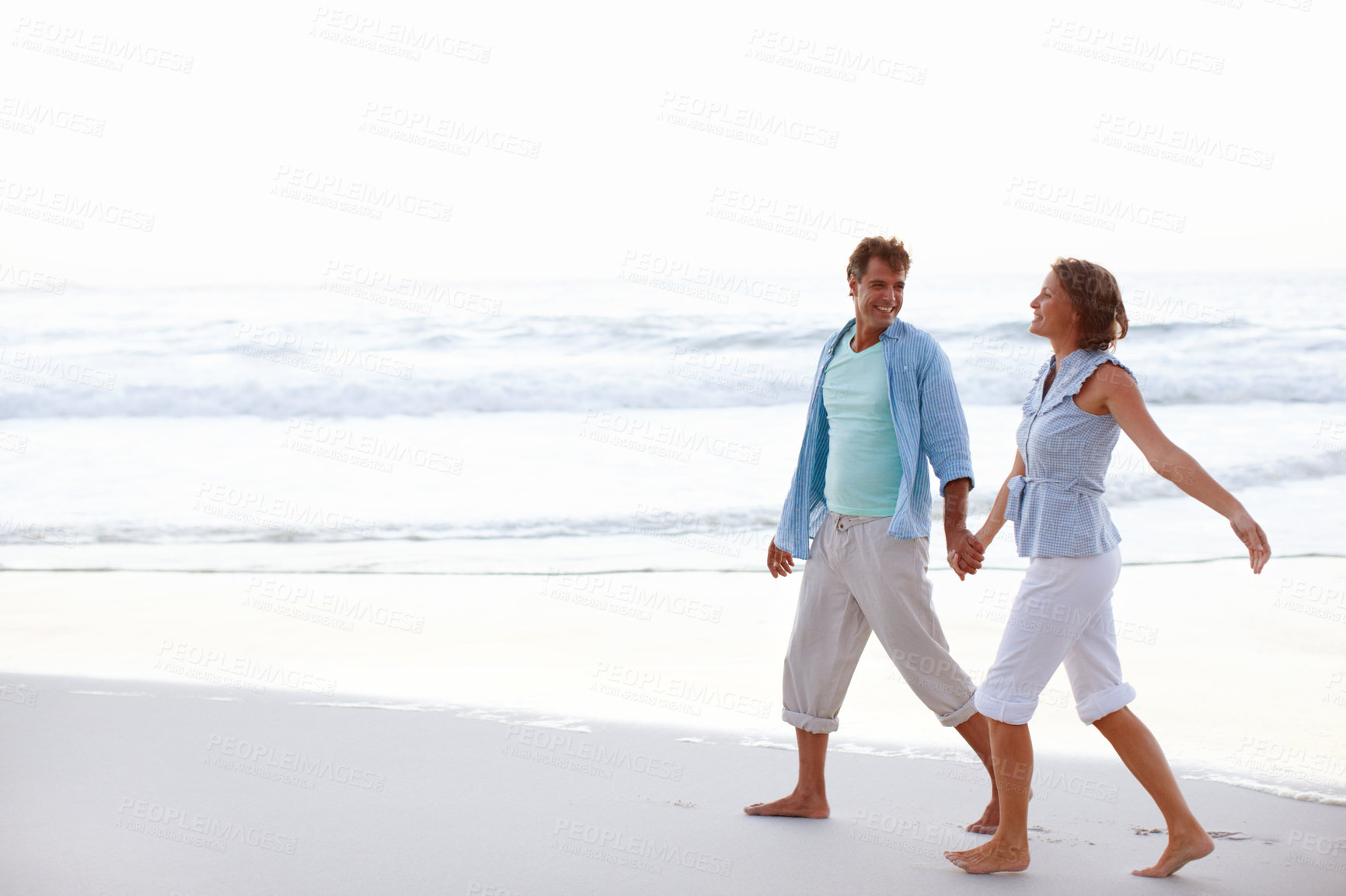 Buy stock photo Couple, holding hands and walking on beach with love, summer vacation and happy at sky space. Mature man, woman or freedom at ocean for anniversary, romantic trip and commitment gesture in Australia