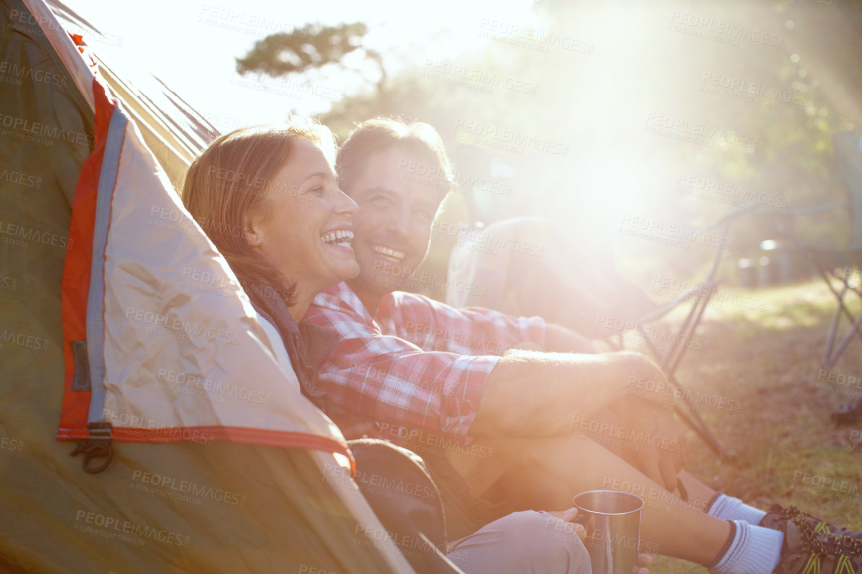 Buy stock photo Nature, couple and laughing by tent for camping, holiday and travel vacation with bonding in wilderness. Outdoor, man and woman with joke for funny memory, adventure and campsite with coffee by flare