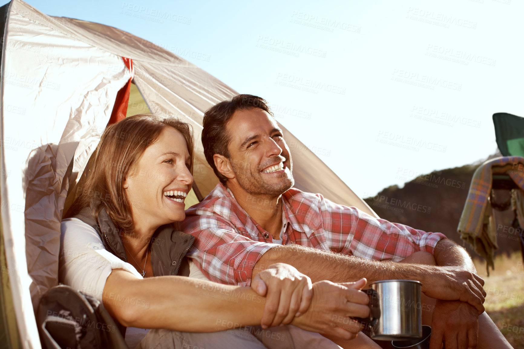 Buy stock photo A happy couple sitting at the entrance of their tent