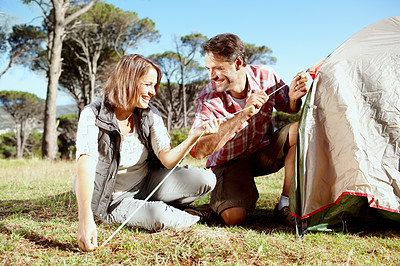 Buy stock photo A young couple securing their tent
