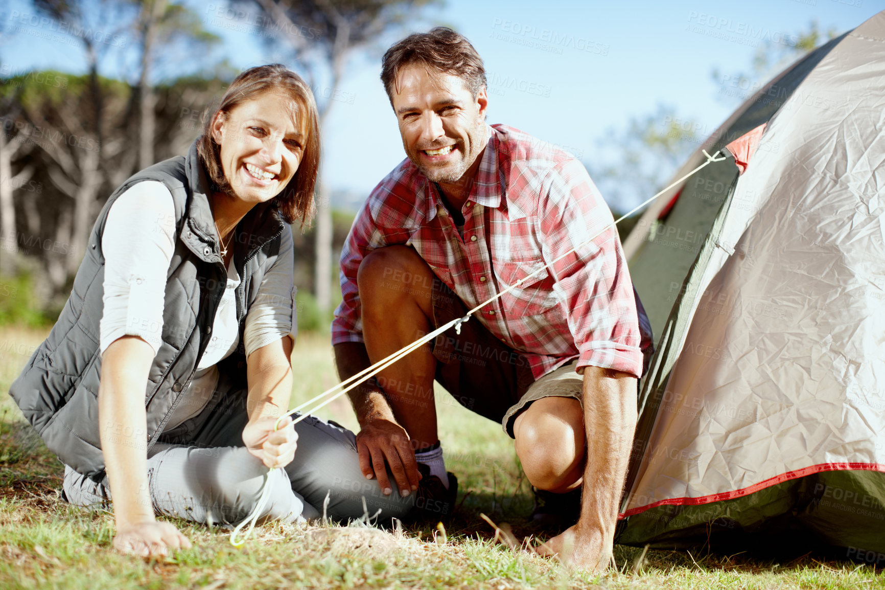 Buy stock photo Portrait of a young couple setting up their tent