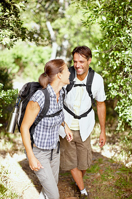 Buy stock photo A young couple laughing while walking with their camping gear on their backs