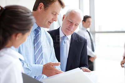 Buy stock photo Focused businesspeople going through documents together in an informal meeting 