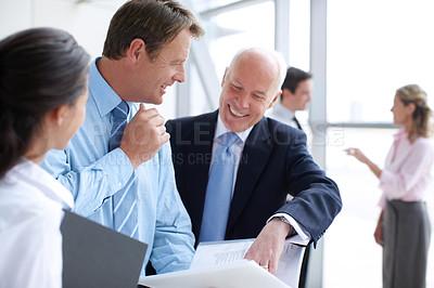 Buy stock photo Positive businesspeople going through documents together in an informal meeting 
