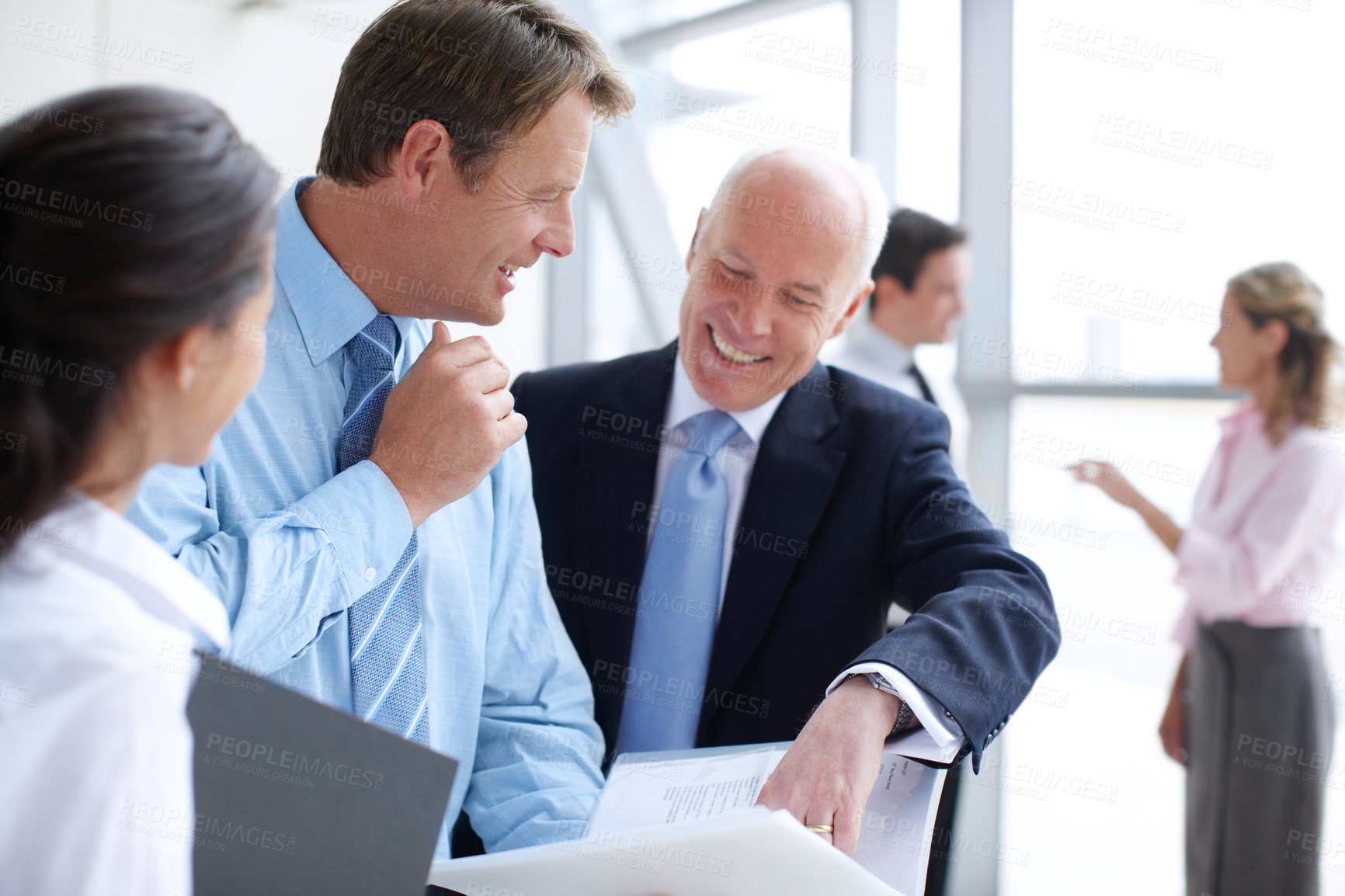 Buy stock photo Positive businesspeople going through documents together in an informal meeting 