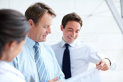 Buy stock photo Happy business executives going through documents together in an informal meeting 