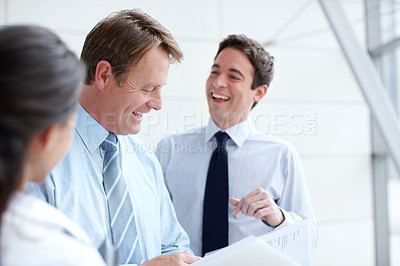 Buy stock photo Laughing business executives going through documents together in an informal meeting 