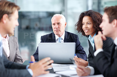 Buy stock photo Corporate coworkers sitting at a table during a meeting and using a laptop 
