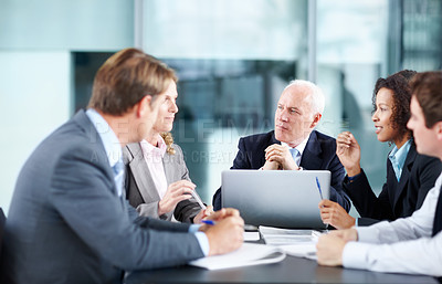 Buy stock photo Focused executives sitting at a table during a meeting and using a laptop 