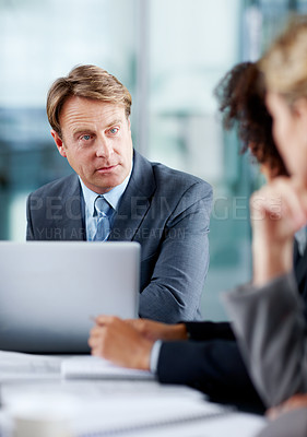 Buy stock photo Focused mature executive listening to his colleagues in a meeting while sitting with a laptop