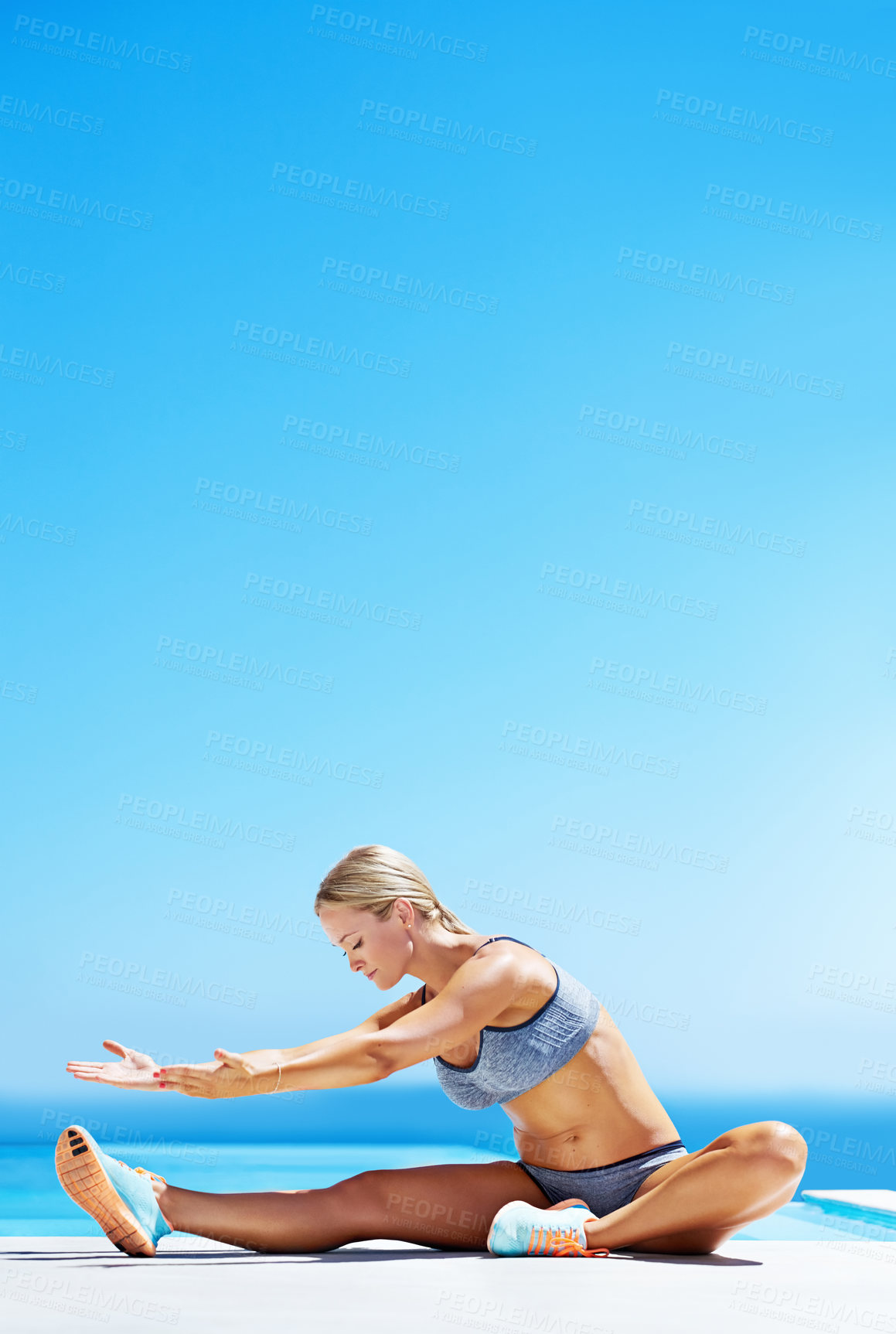 Buy stock photo Shot of a young woman working out on a patio under a blue sky