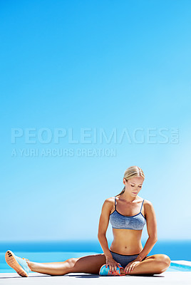 Buy stock photo Shot of a young woman working out on a patio under a blue sky