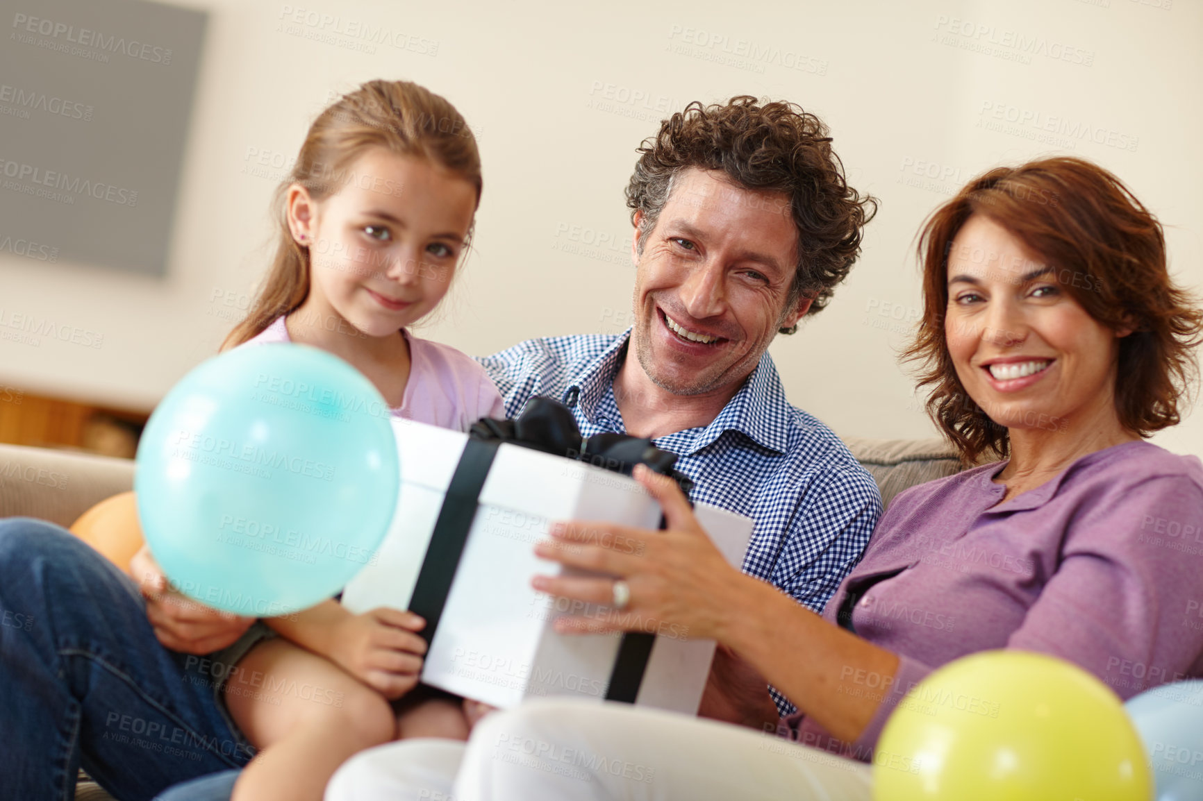 Buy stock photo Shot of a family siting in the living room with a gift